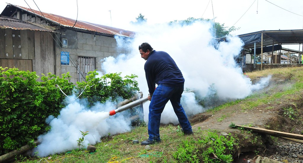 Un hombre fumigando una casa.